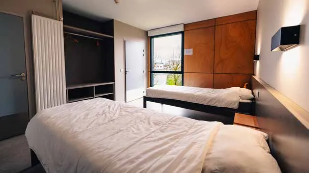 Une chambre standard du Centre sportif de l’Aube : deux lits simples, une grande fenêtre, un placard ouvert