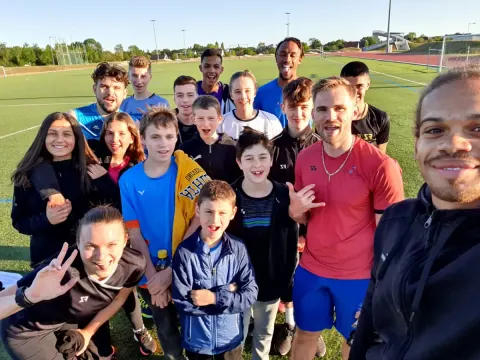 Un groupe de jeunes stagiaires et leurs coachs sur le terrain extérieur