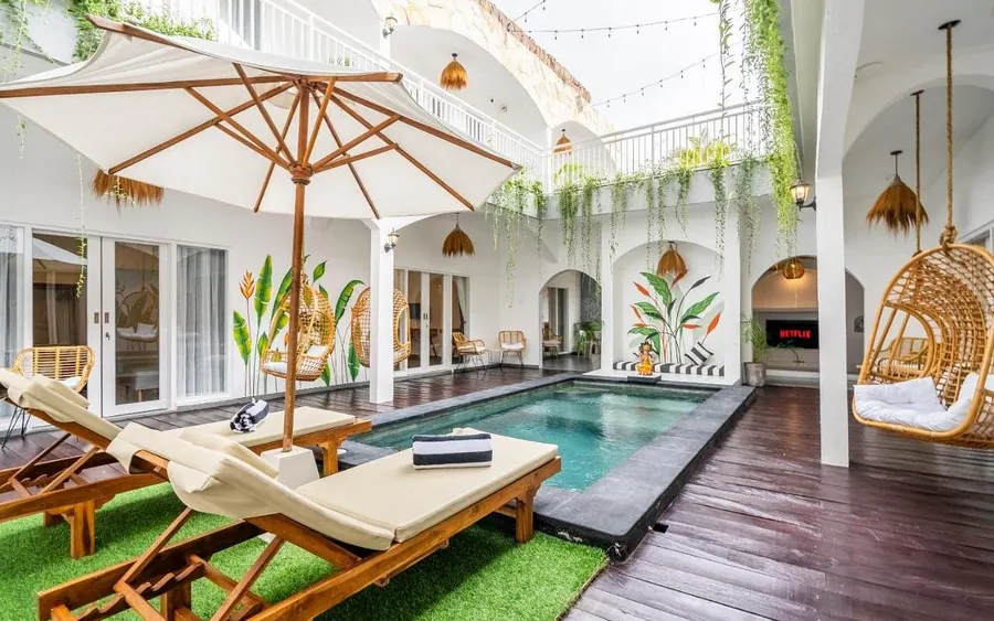 La cour de l’hôtel 2026 : piscine, transats et parasol entre des murs blancs